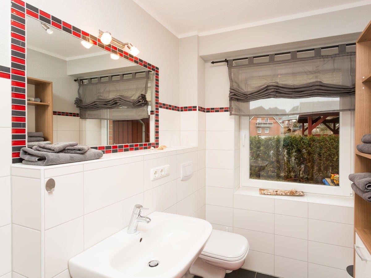 Badezimmer mit Waschbecken, Toilette und Fenster mit Blick nach draußen.