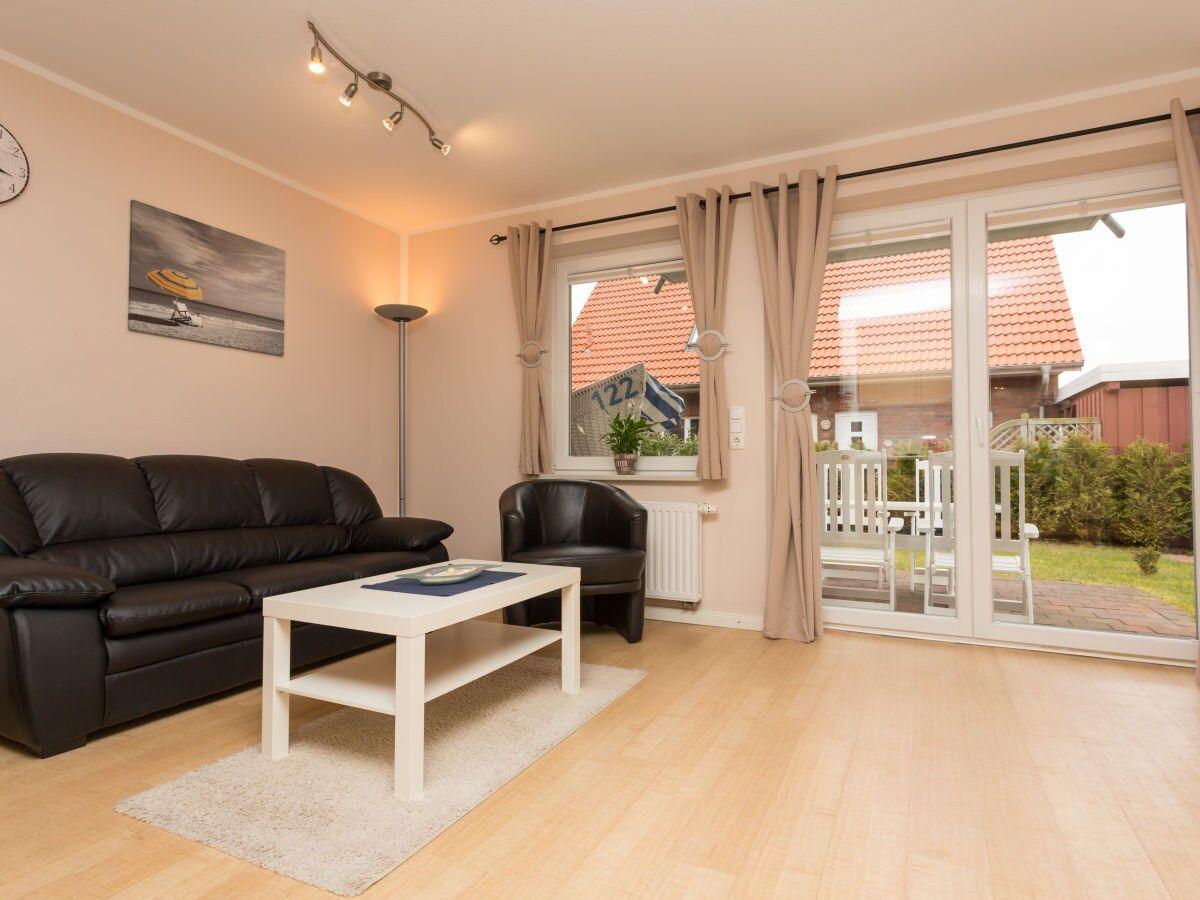 Wohnzimmer mit Sofa, Couchtisch und Terrasse. Blick auf Garten und Nachbarhaus.
