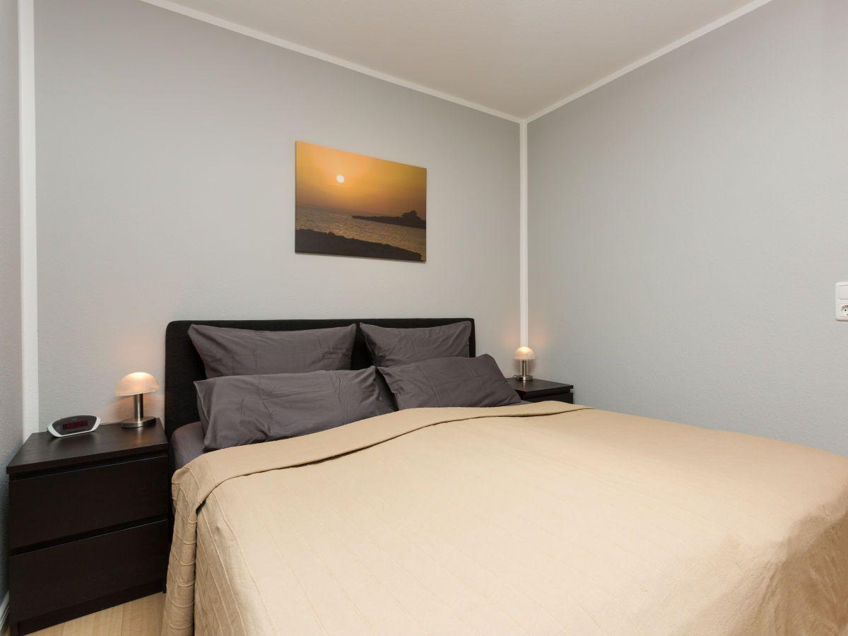 Schlafzimmer mit Bett, Nachttischen und Wandbild.