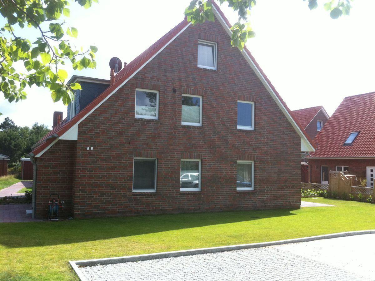 Rotes Ziegelhaus mit Gartenterrasse und grünem Rasen
