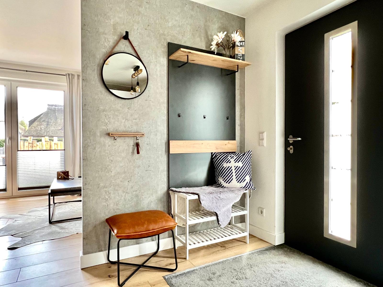 Eingangsbereich mit Wandgarderobe, Spiegel und Sitzgelegenheit.