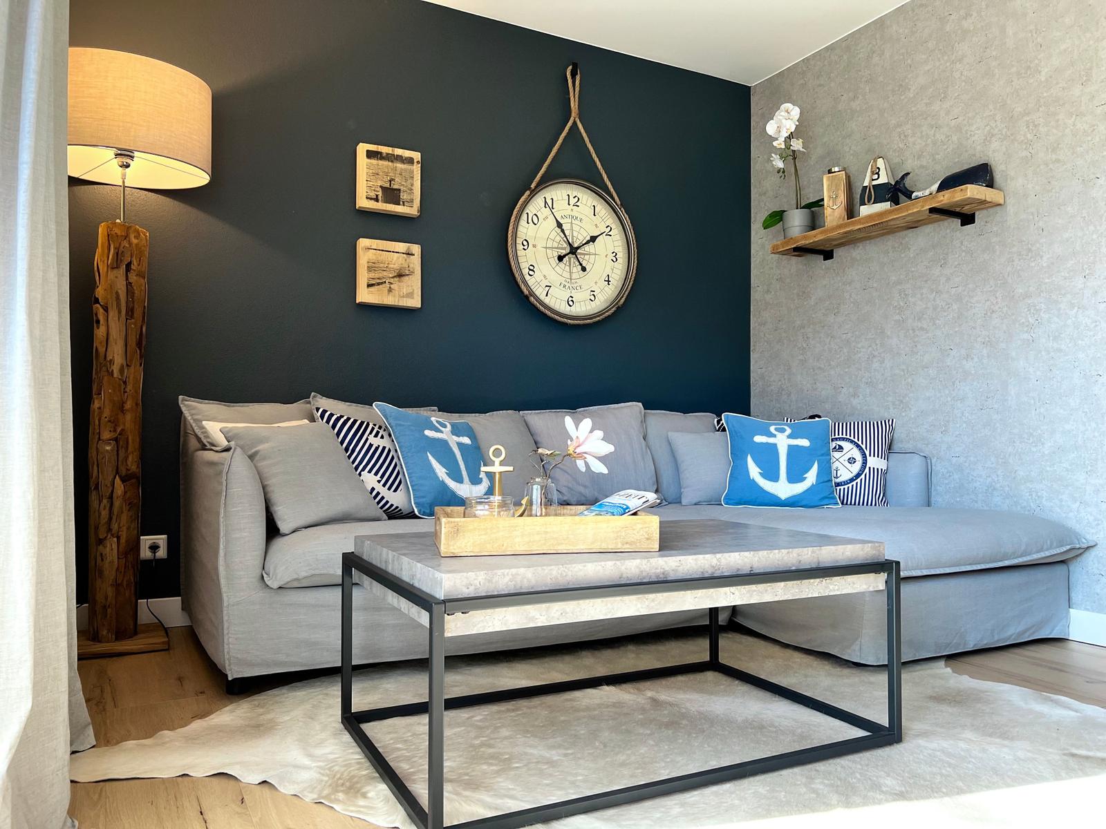 Wohnzimmer mit Sofa, Tisch und Wanduhr.