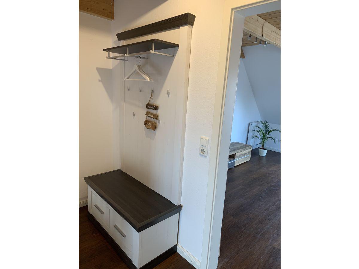 Eingangsbereich mit Kleiderständer und Sitzbank. Durchgang in Wohnraum mit Pflanze.