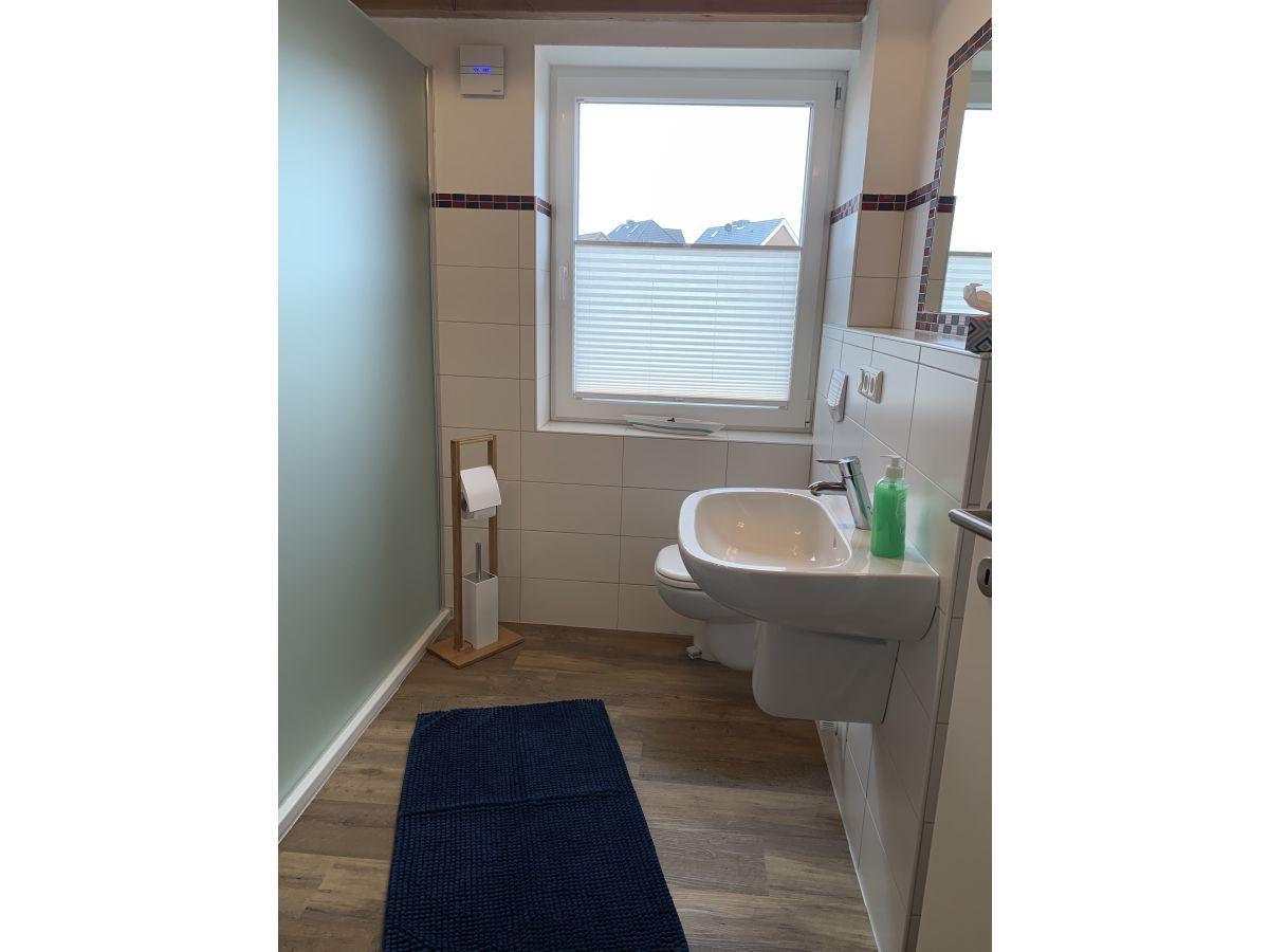 Badezimmer mit Waschbecken, Toilette und Fenster mit Jalousie.