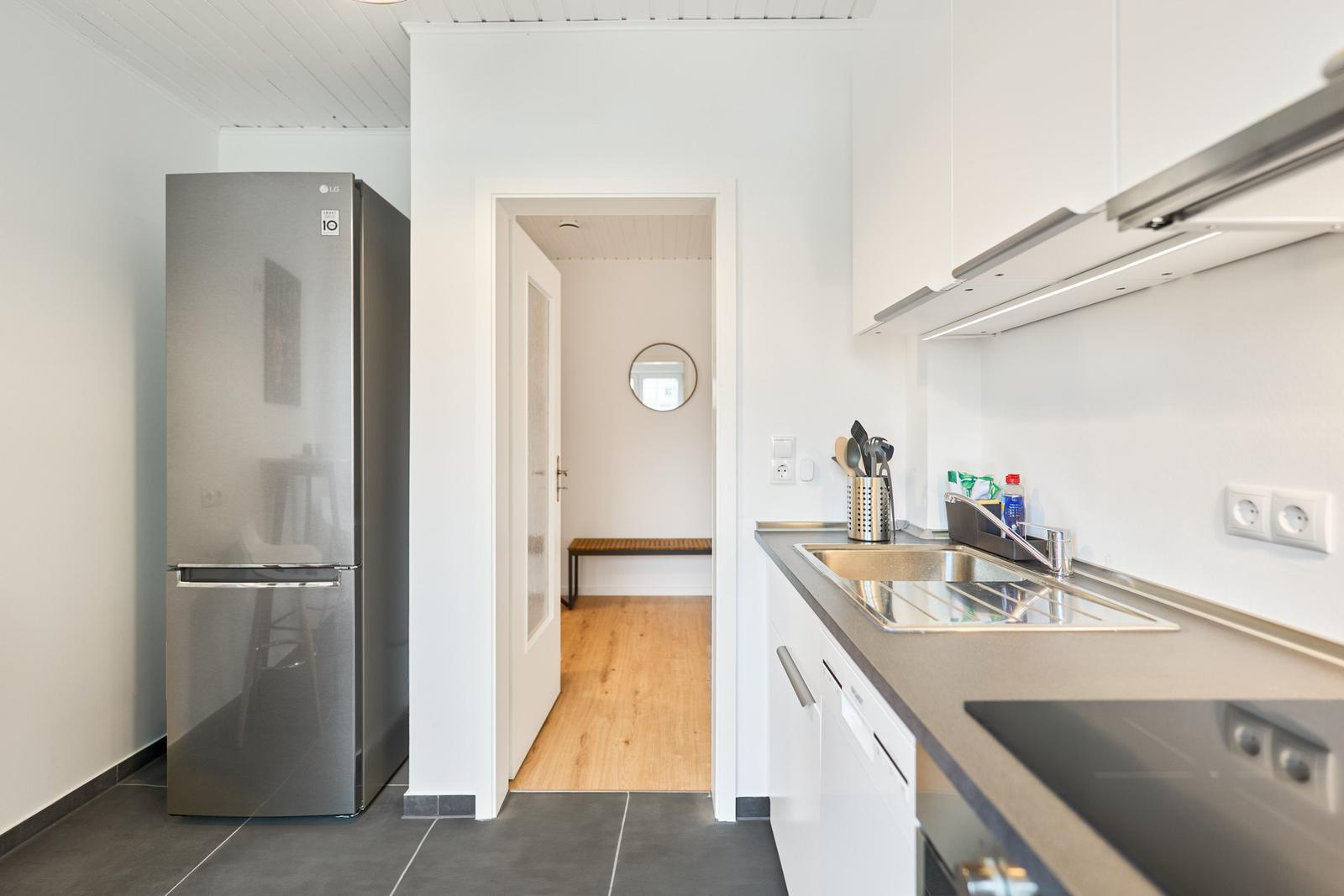 Küche mit Spüle, Kühlschrank und Durchgang zur nächsten Raum.