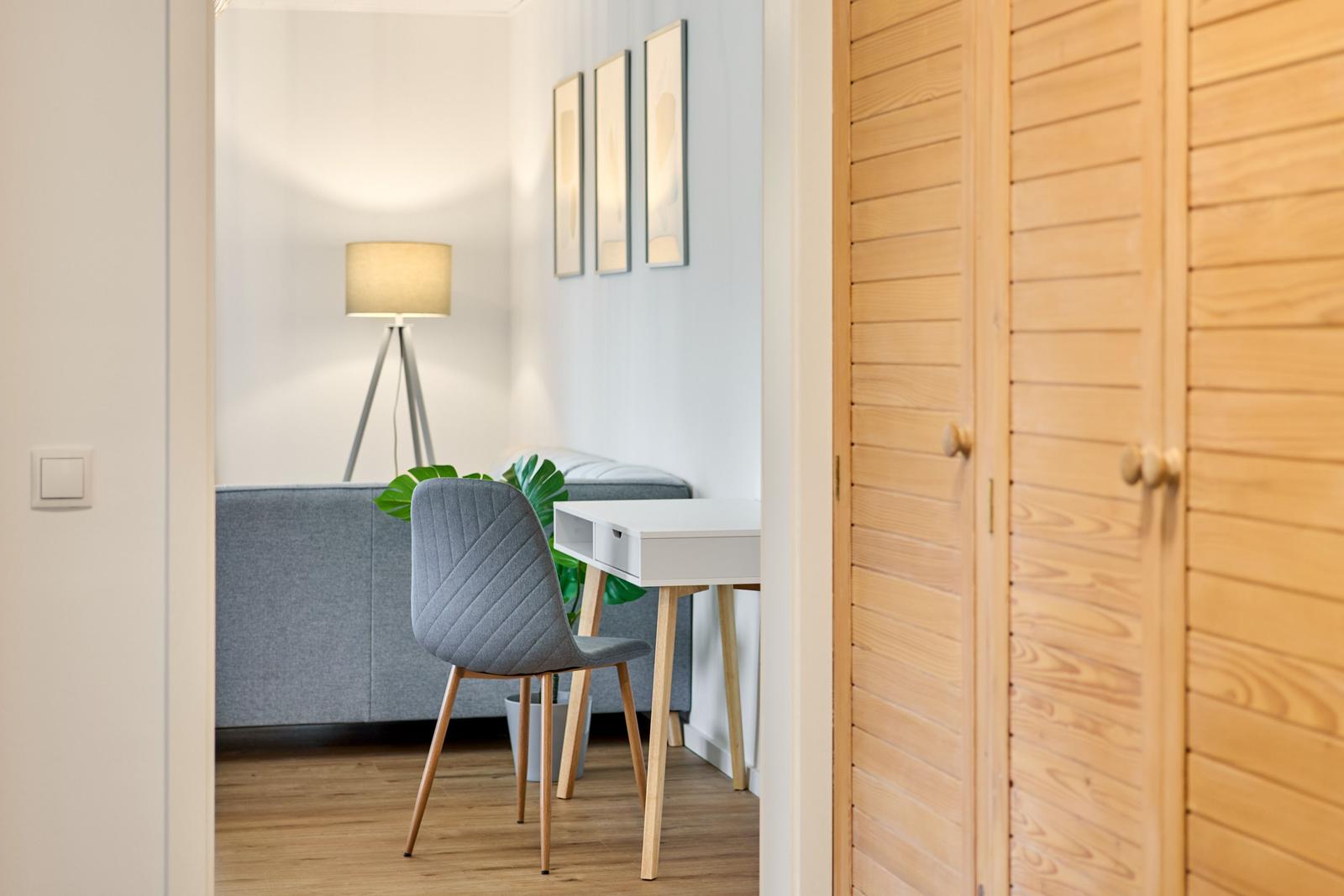 Ein Raum mit Schreibtisch, Stuhl und Sofa. Holztür und Wanddekoration sind sichtbar.