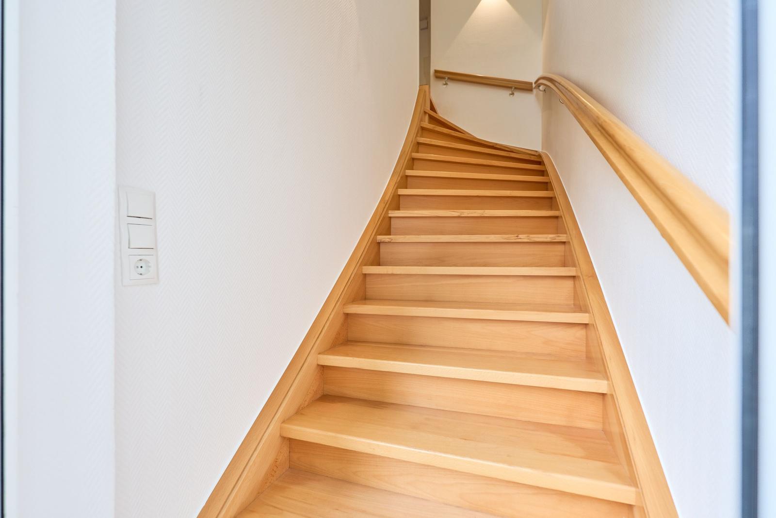 Holztreppenhaus mit Geländer und Licht an der Wand