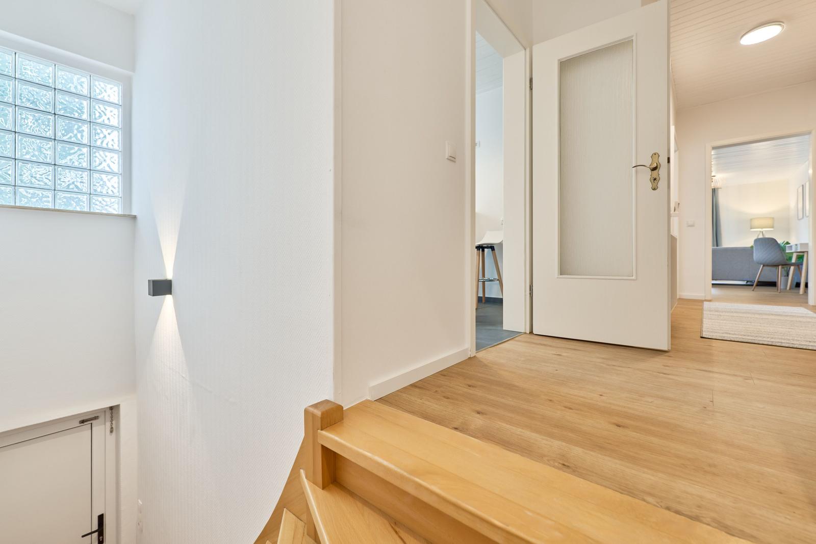 Helle Eingangshalle mit Holzboden und Glasblöcken. Tür führt in Wohnbereich.