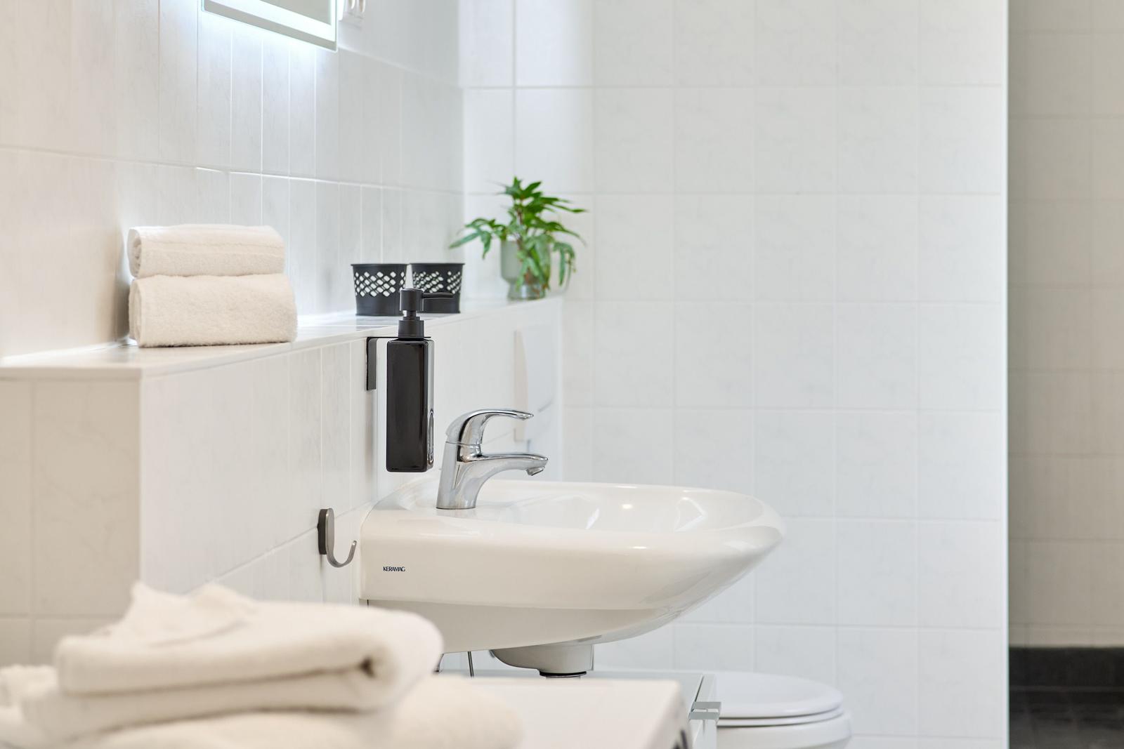 Badezimmer mit Waschbecken, Handtuch und Pflanze.