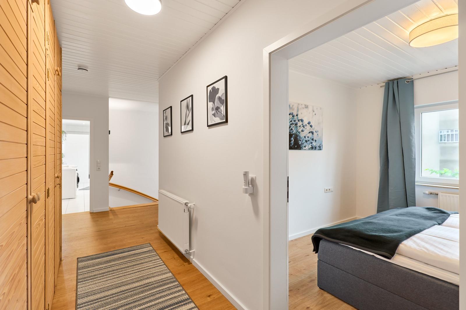Flur mit Schlafzimmer, Holzboden und Wandbildern