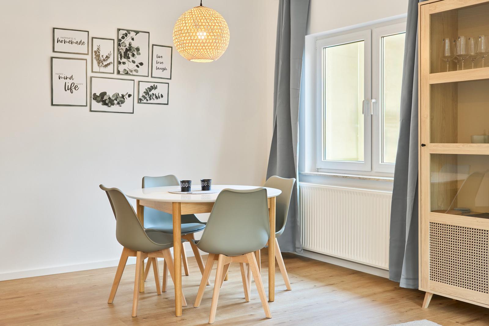 Essbereich mit runden Tisch, vier Stühlen und Wanddekoration.