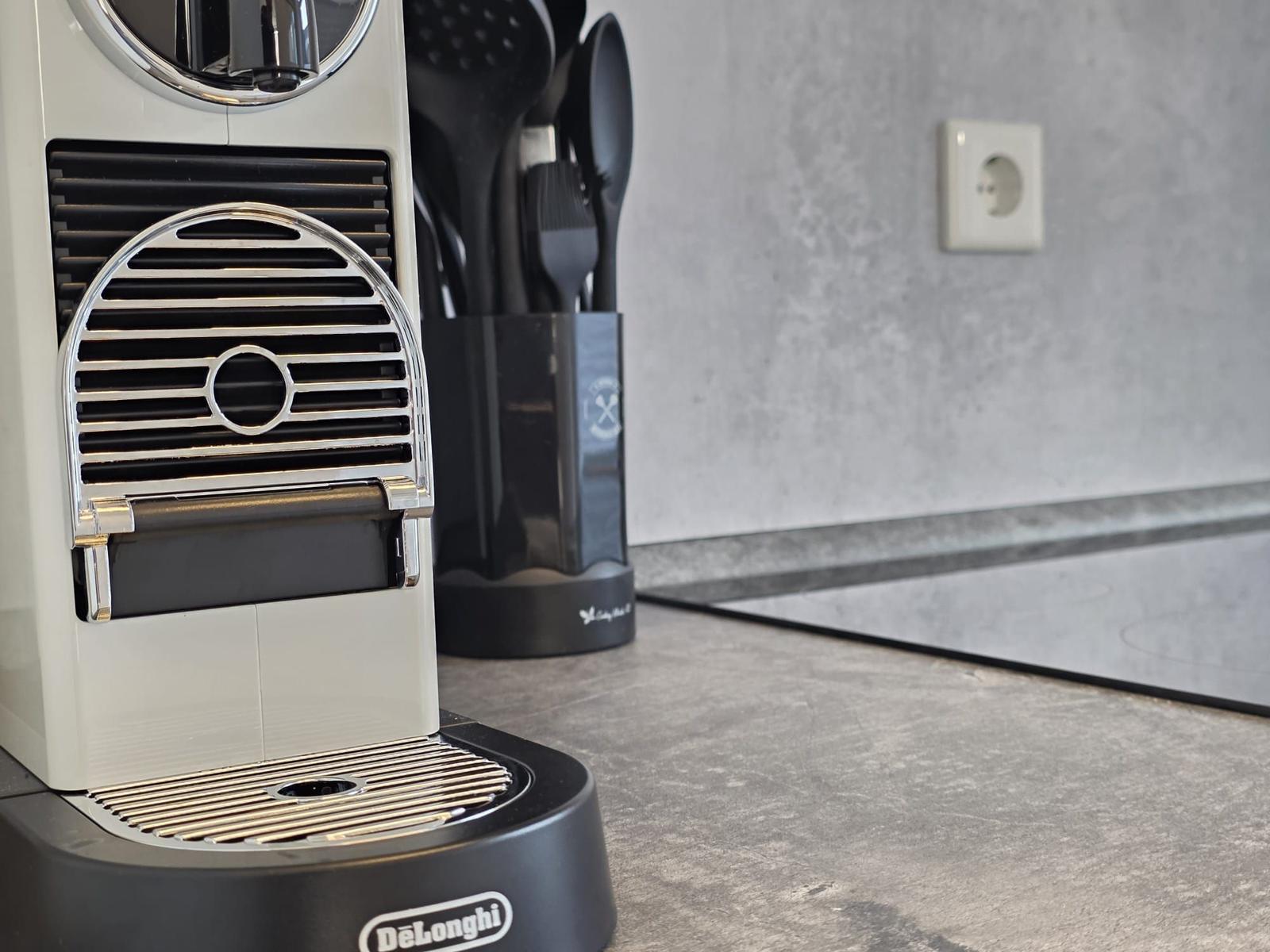 Espresso-Maschine auf Küchenarbeitsfläche mit Kochutensilien im Hintergrund.