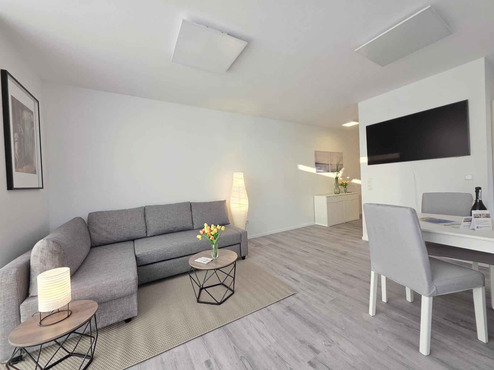 Wohn- und Essbereich mit Sofa, Esstisch und Fernseher.