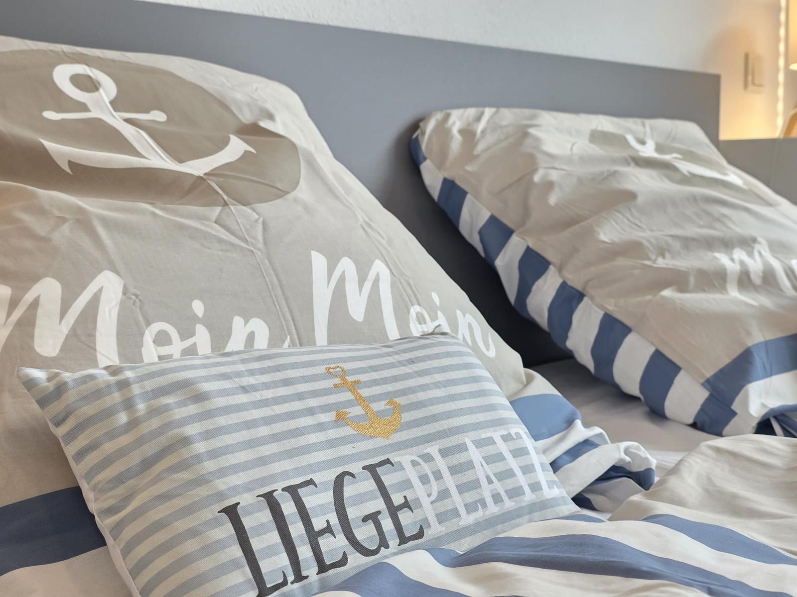 Bettkopfteil mit Kissen und Bettwäsche im maritimen Stil.