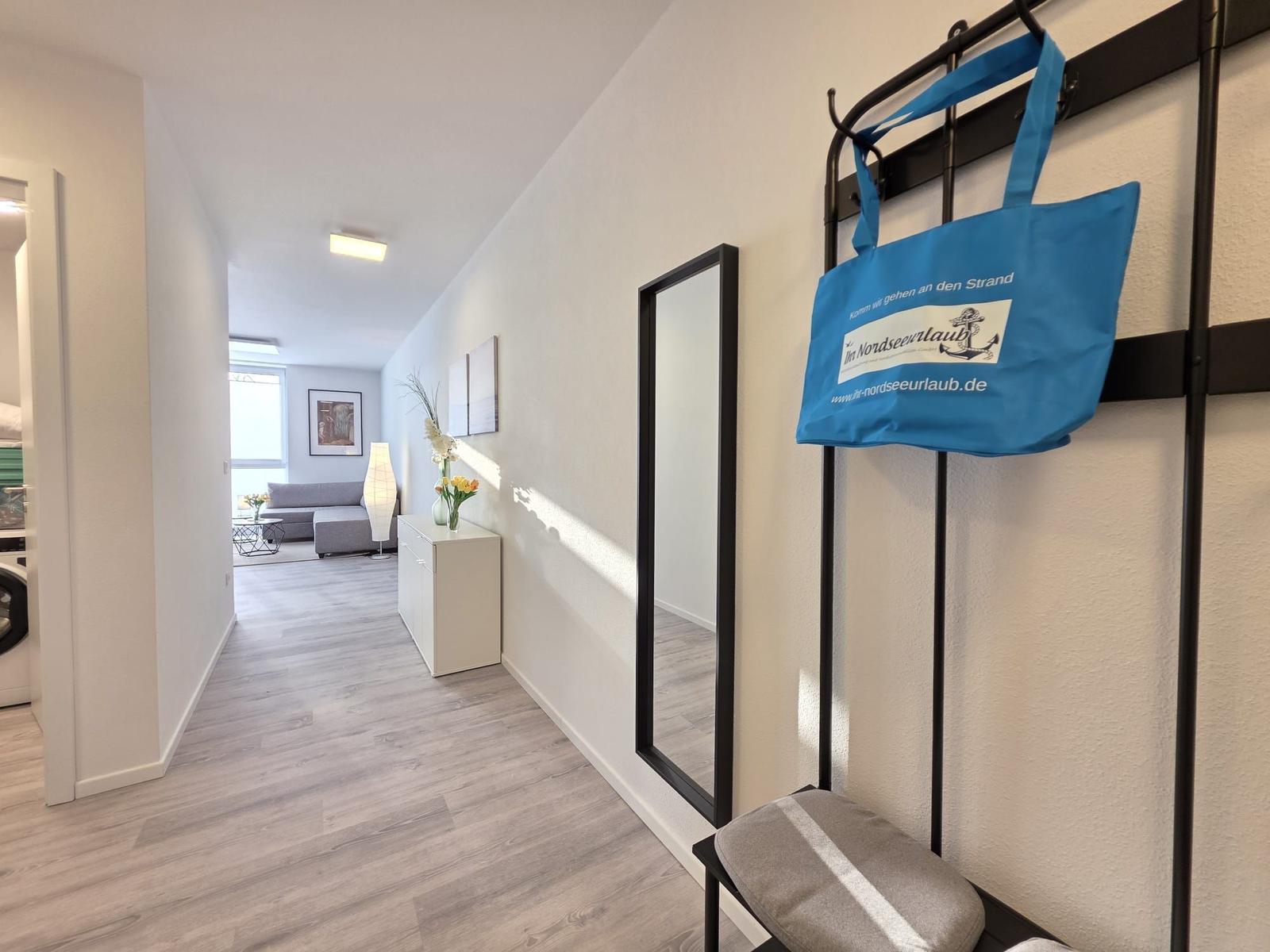 Flur mit Spiegel, blauer Tasche und Blick ins Wohnzimmer.