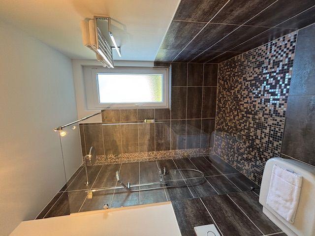 Shower with glass wall, mosaic wall, and window