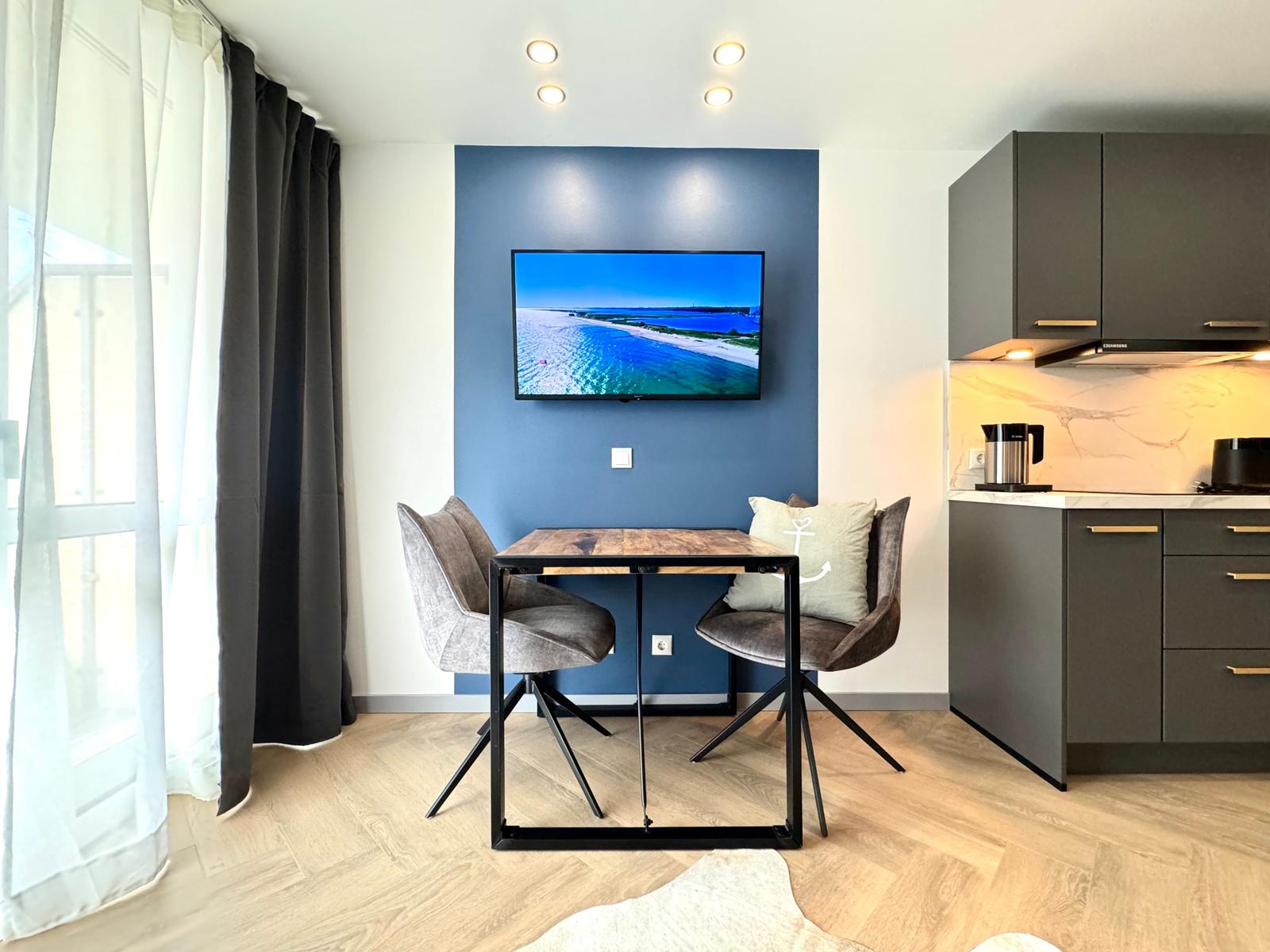 Essbereich mit TV und Küchenzeile in moderner Wohnung.