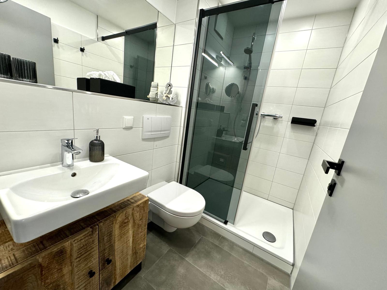 Badezimmer mit Dusche, Waschbecken und Toilette.