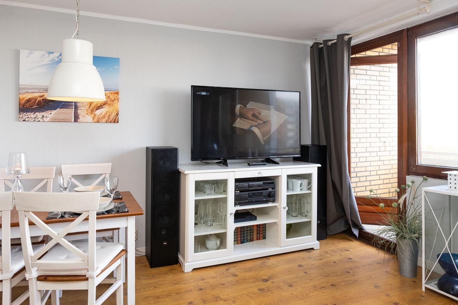 Living and dining area with TV, table, chairs, and window.