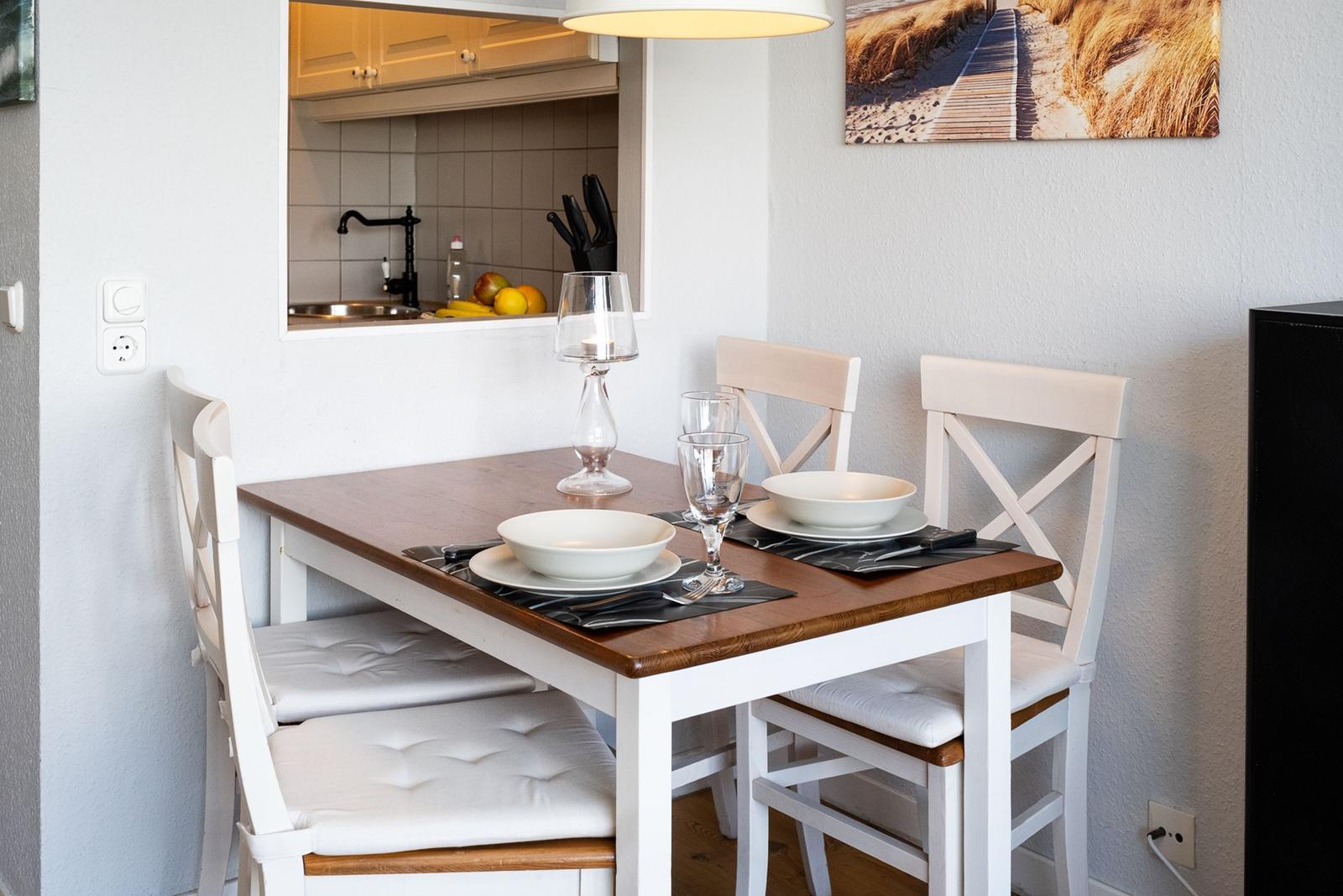 Dining area with table and chairs, kitchen area in background