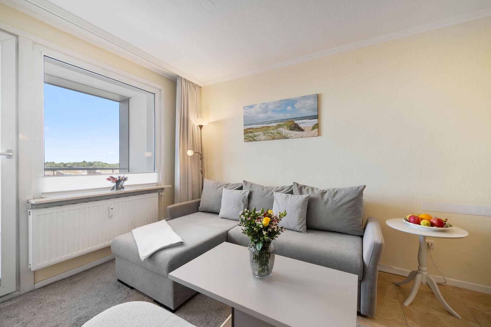 Wohnzimmer mit Sofa, Tisch und Fensterblick