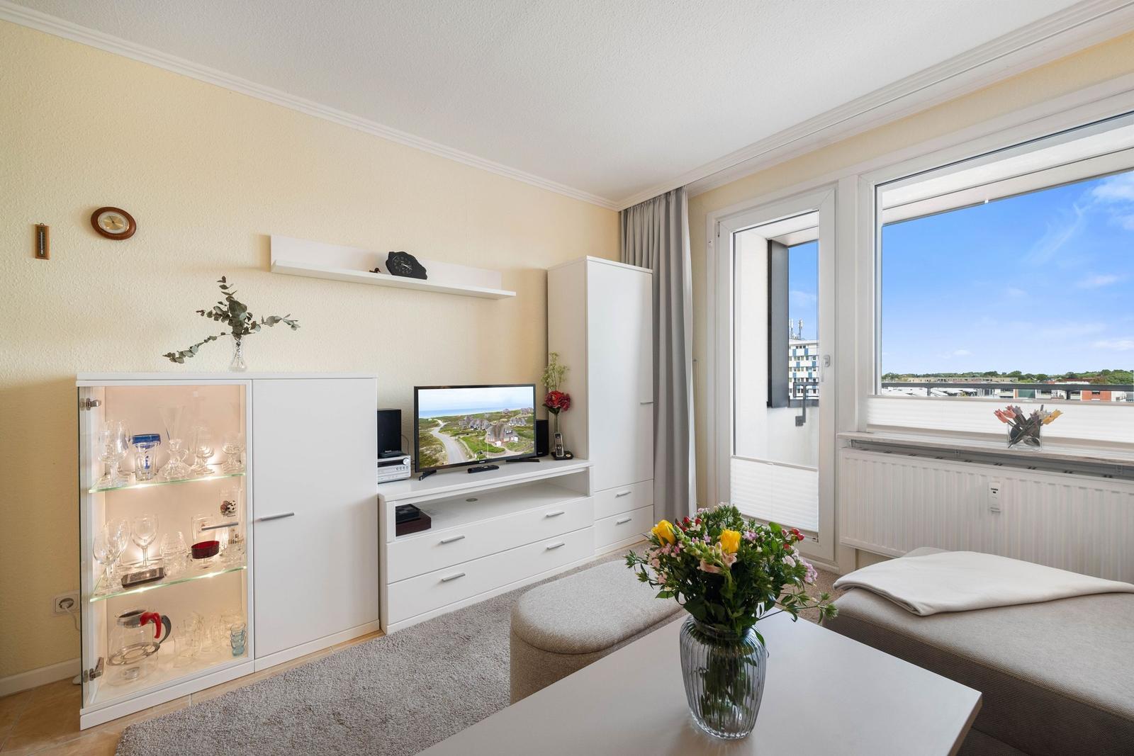 Wohnzimmer mit Fernseher, Glasvitrine und Blick auf die Stadt