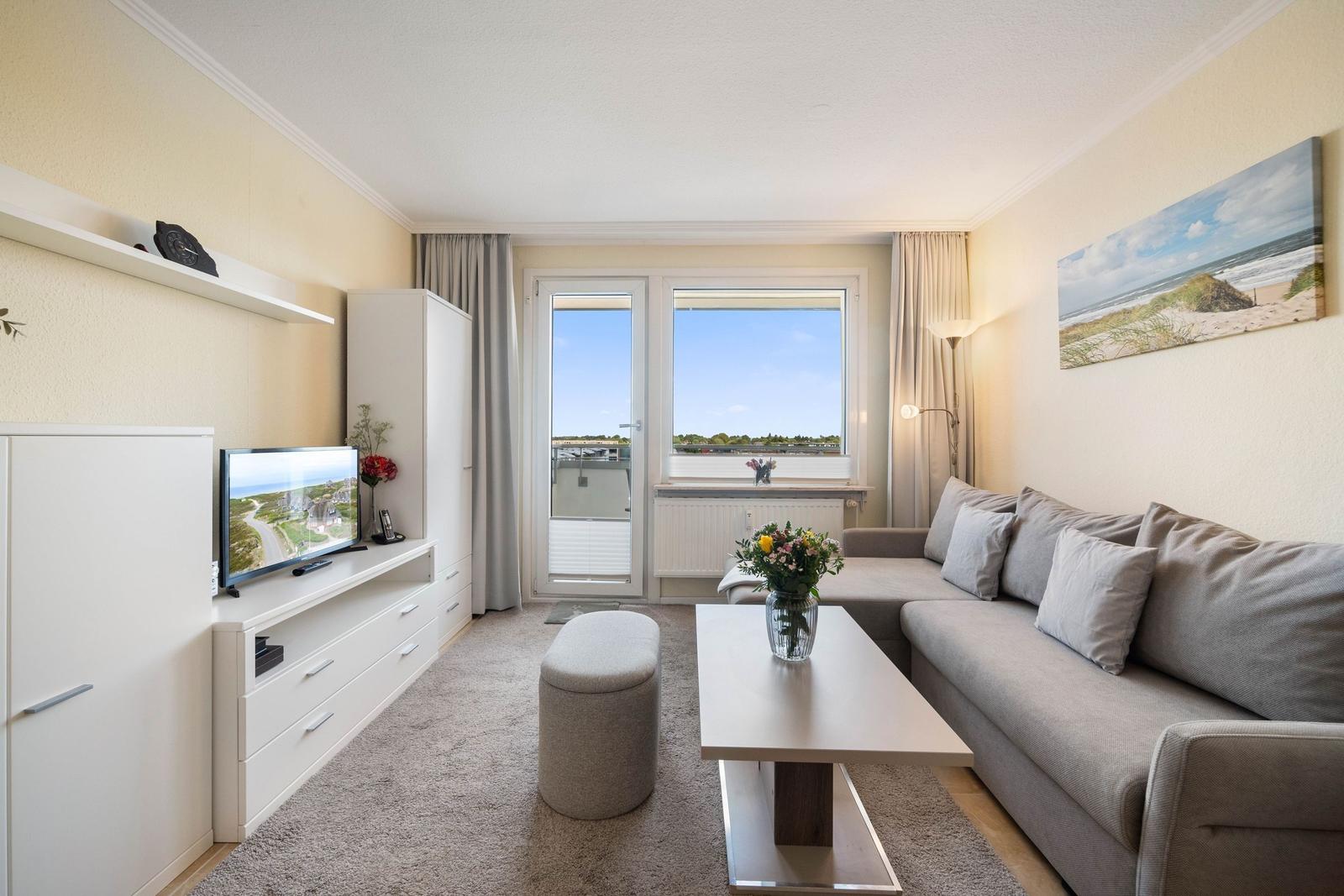 Wohnzimmer mit Sofa, Couchtisch und TV. Fenster mit Blick auf den Hafen.