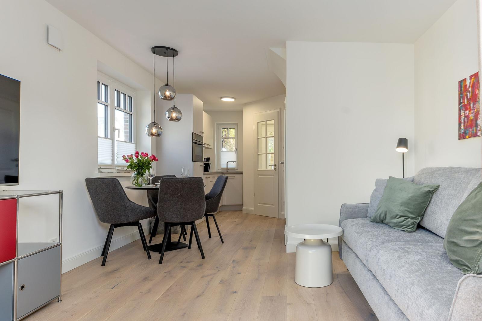 Wohn- und Essbereich mit Sofa, Esstisch und Küche.