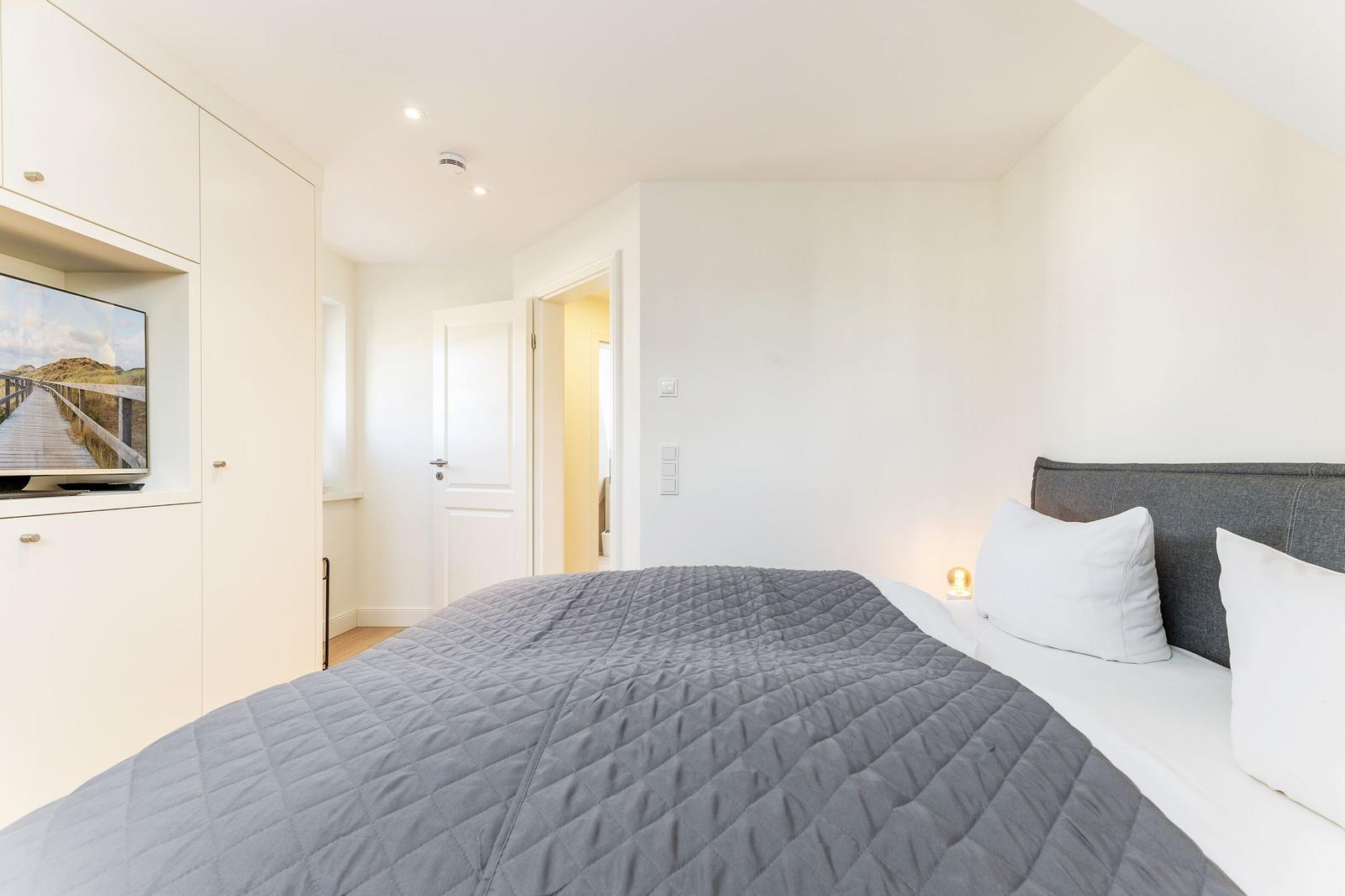 Schlafzimmer mit Bett, TV und Tür