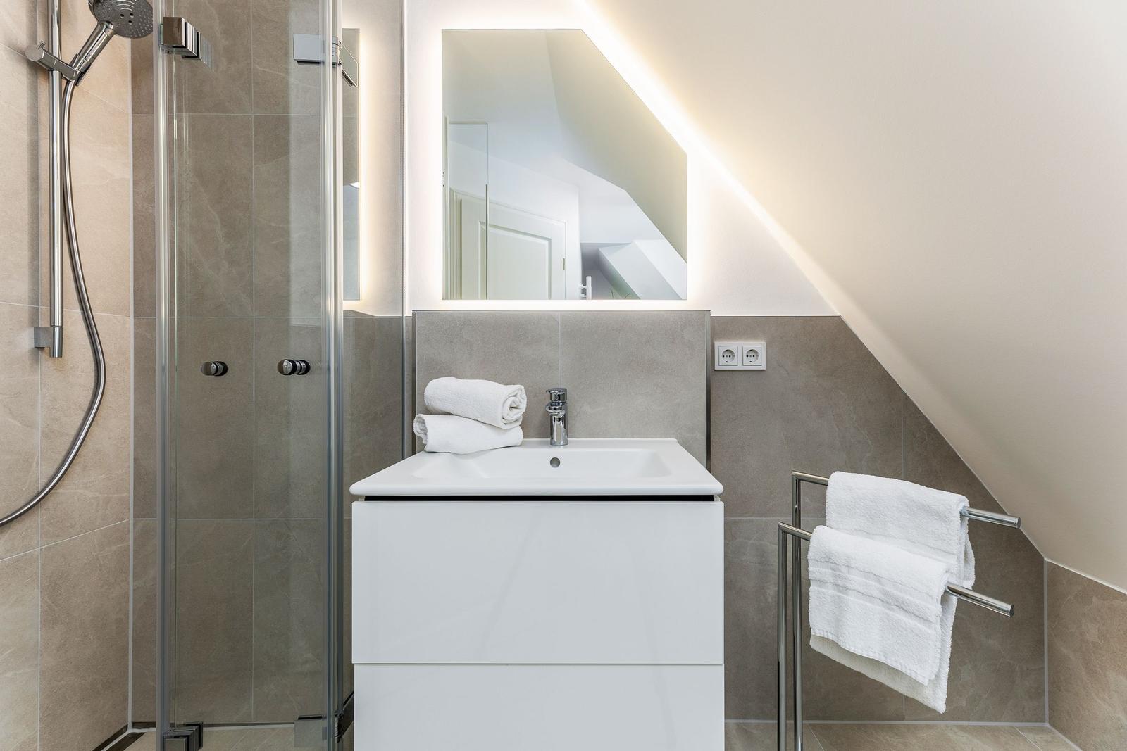 Badezimmer mit Dusche, Waschbecken und Handtüchern