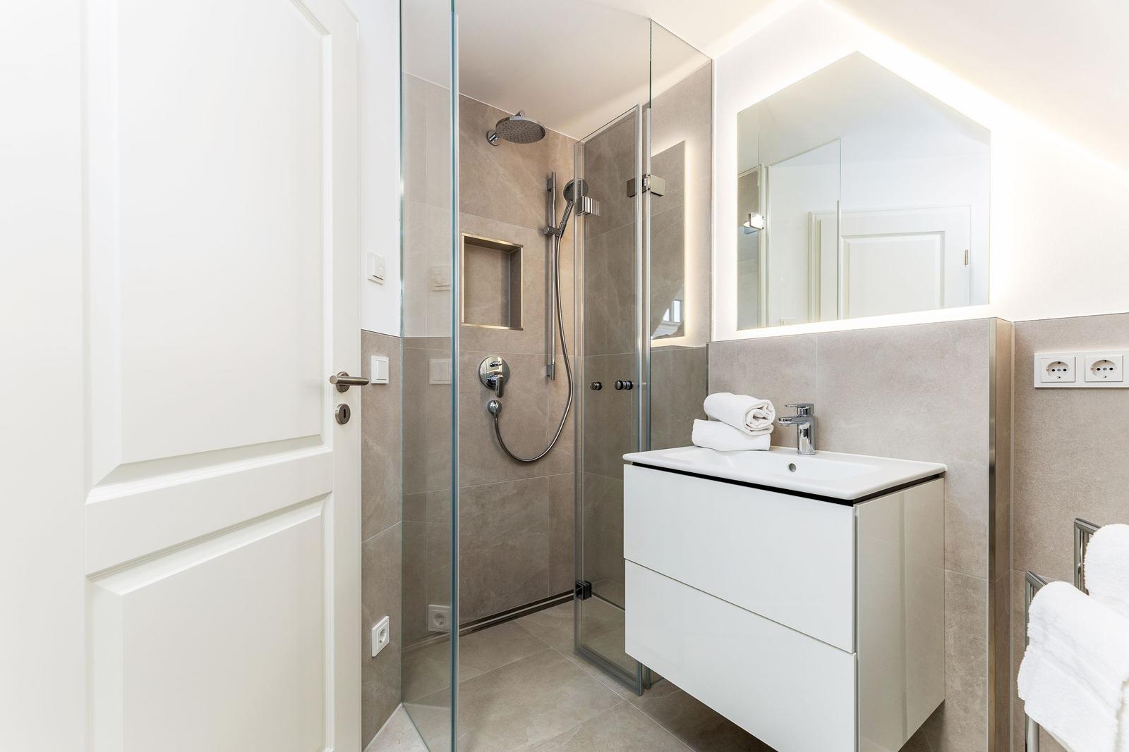 Moderne Badewanne mit Dusche, Waschbecken und Spiegel.