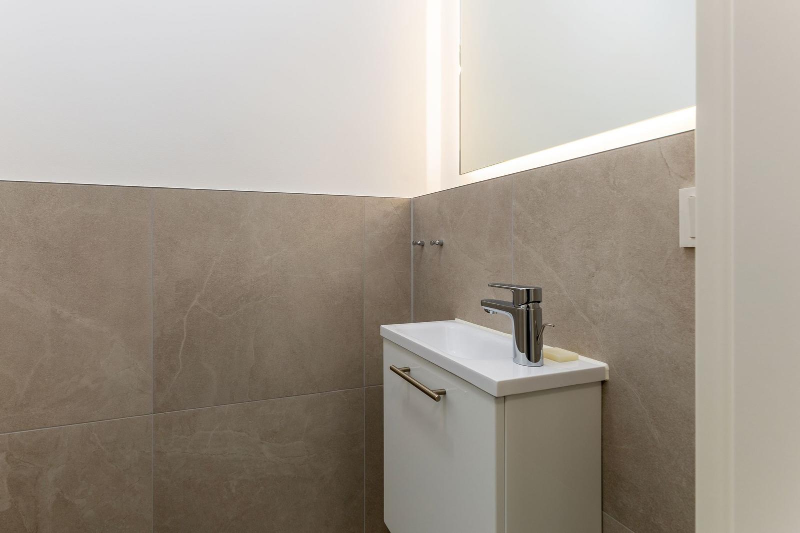 Bad mit Waschbecken, Spiegel und Fliesenwand