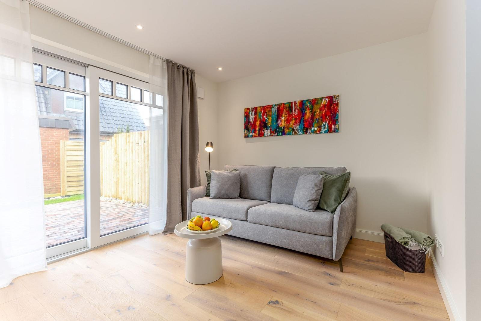 Wohnzimmer mit Sofa, Tisch und Glasfront zur Terrasse.