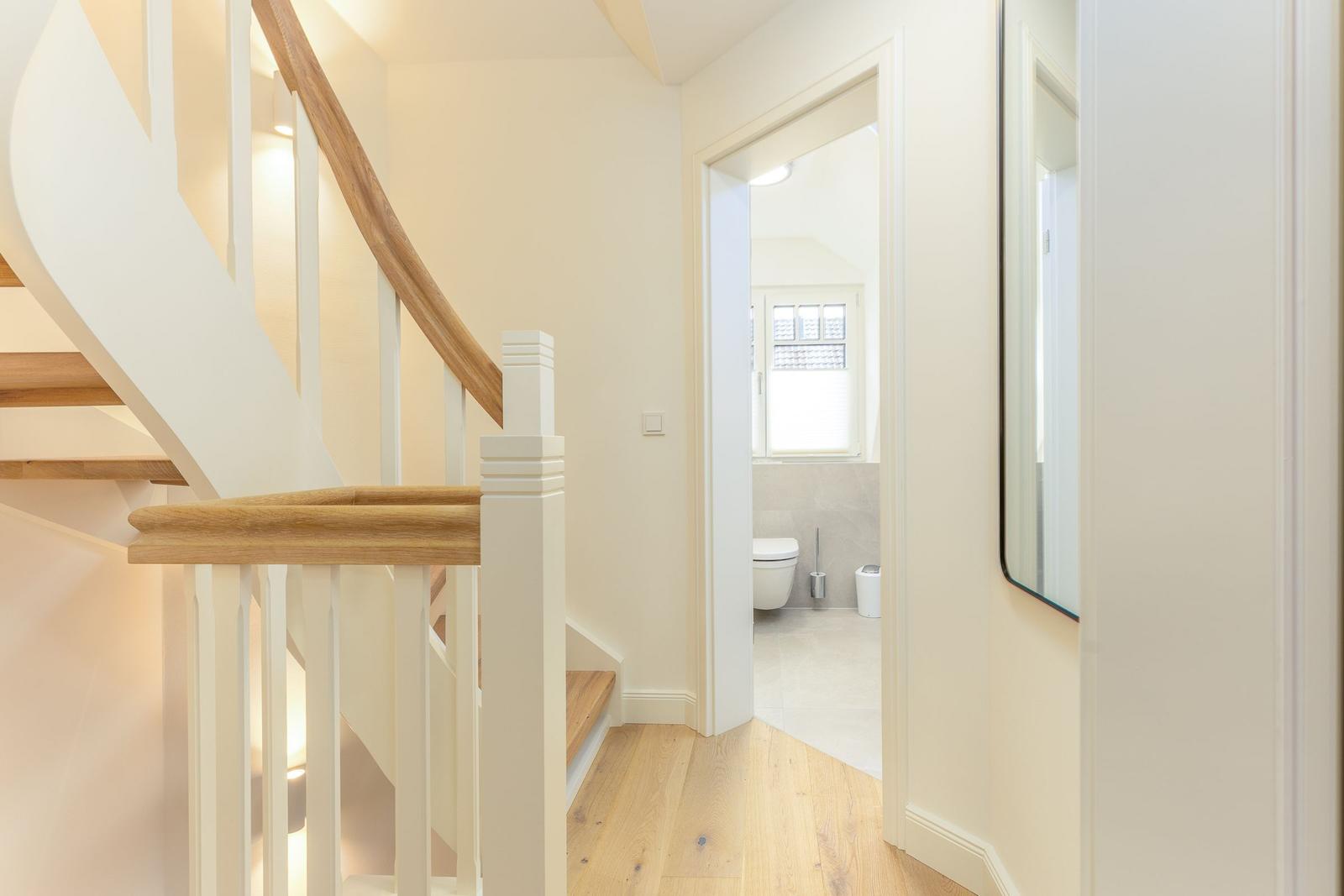 Hausflur mit Treppe und Blick in die Toilette.