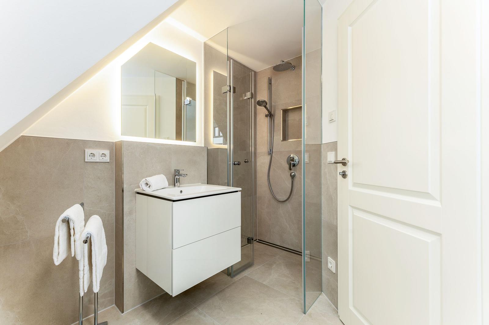 Badezimmer mit Dusche, Waschbecken und Spiegel