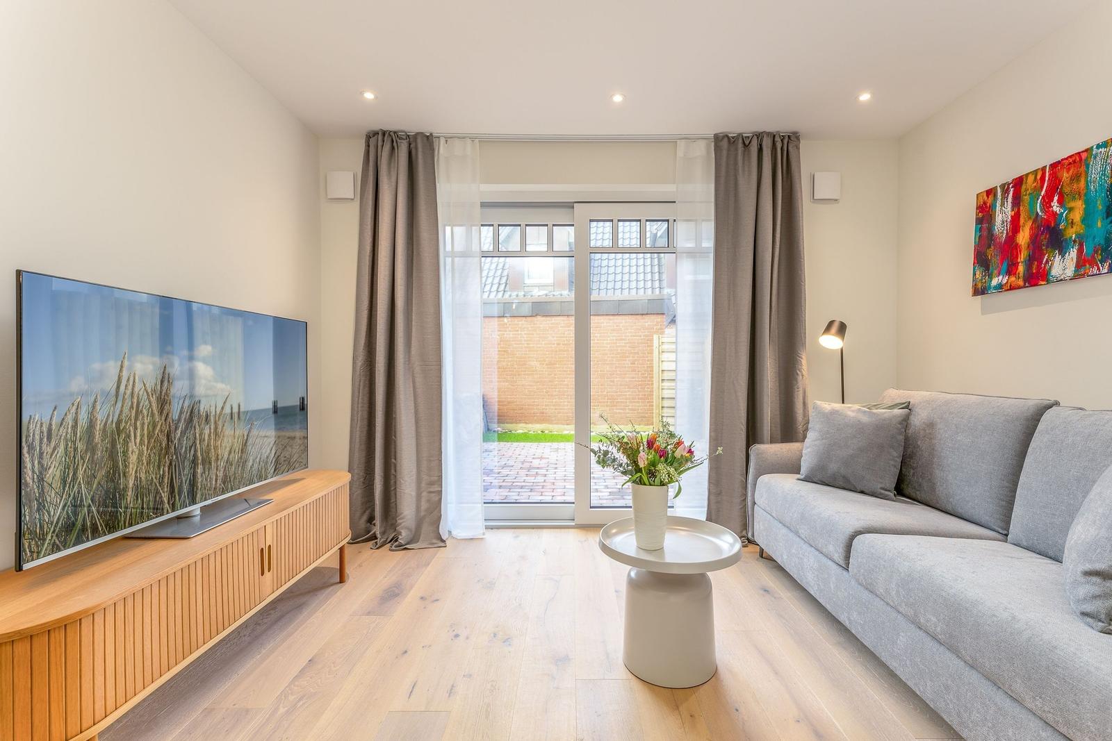 Wohnzimmer mit Sofa, Fernseher und Terrassentür.