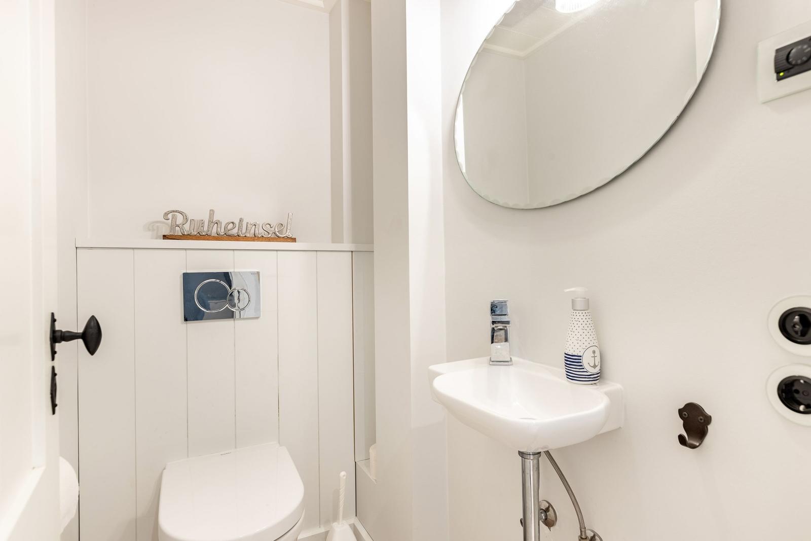 Bad mit Waschbecken, Spiegel und Toilette. Dekoration mit Ankermotiv.