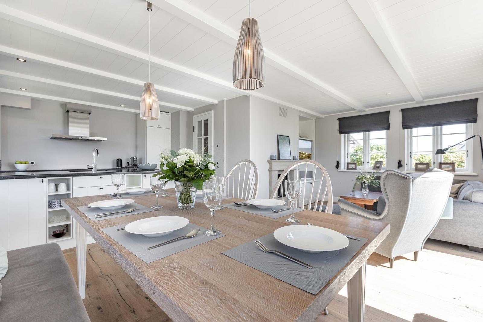 Essbereich mit Holztisch, Stühlen und Küche im Hintergrund.