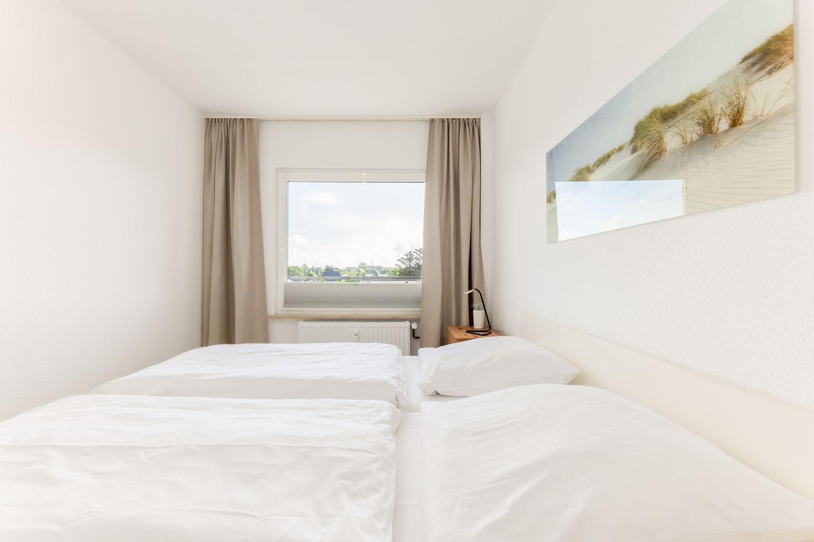 Schlafzimmer mit Doppelbett, Fenster und Wandbild.