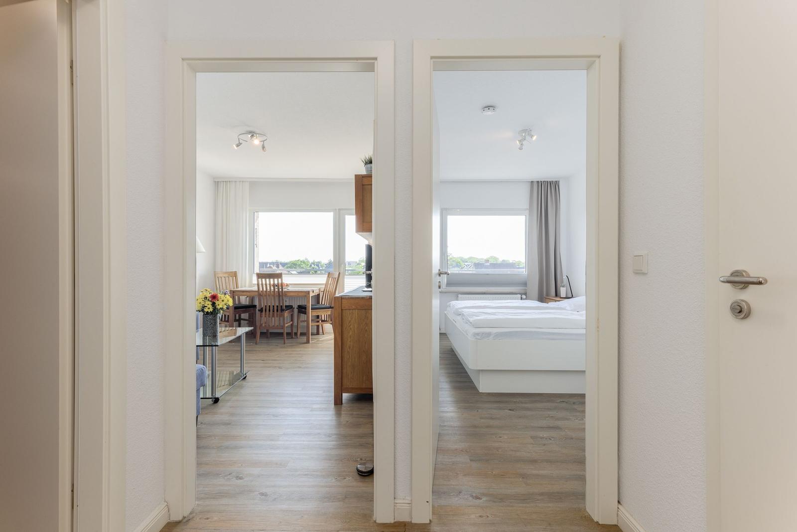 Zwei Räume sind sichtbar: ein Schlafzimmer mit Bett und ein Esszimmer mit Tisch und Stühlen.