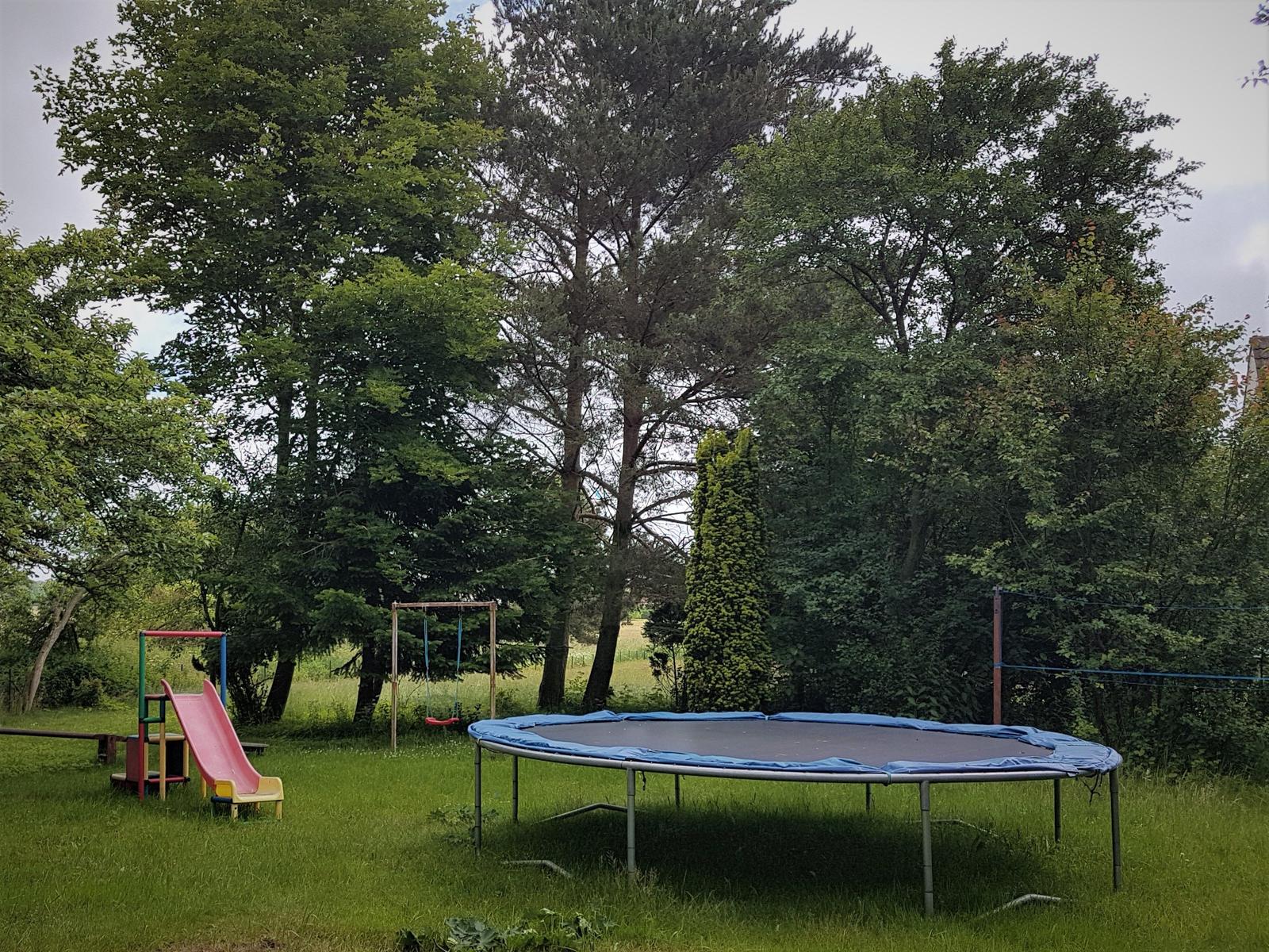 Spielplatz im Gartenbereich mit Wippe, Schaukel und Trampolin