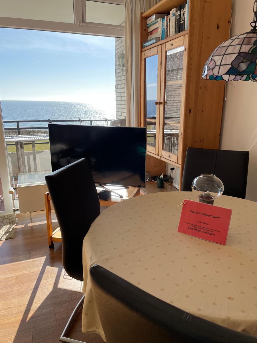 Esszimmer mit Tisch, Stühlen und Meerblick durch großes Fenster.