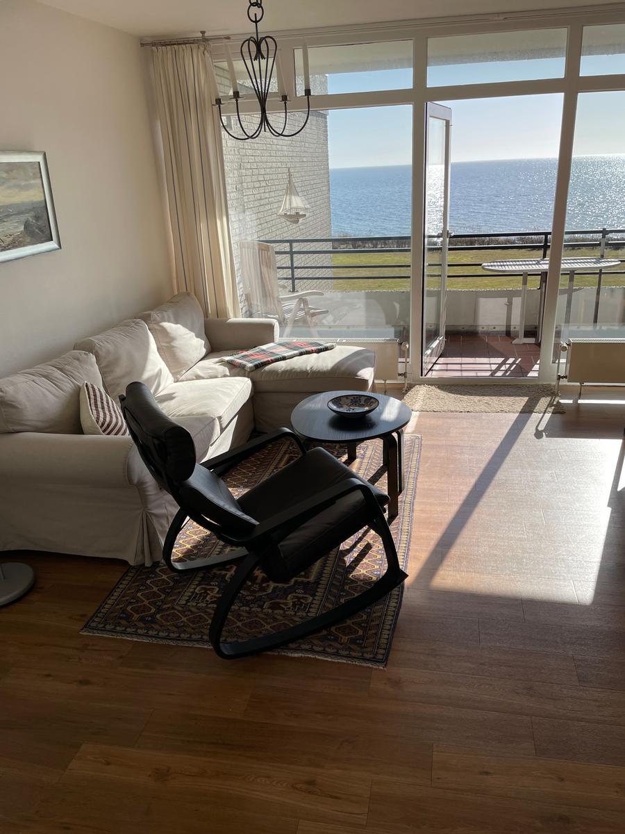 Wohnzimmer mit Sofa, Sessel und Blick aufs Meer.