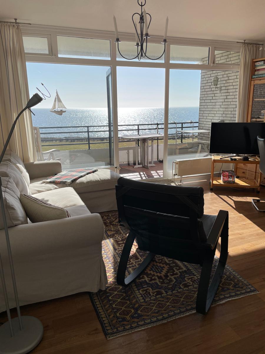 Wohnzimmer mit Blick auf das Meer und Balkon mit Tisch.