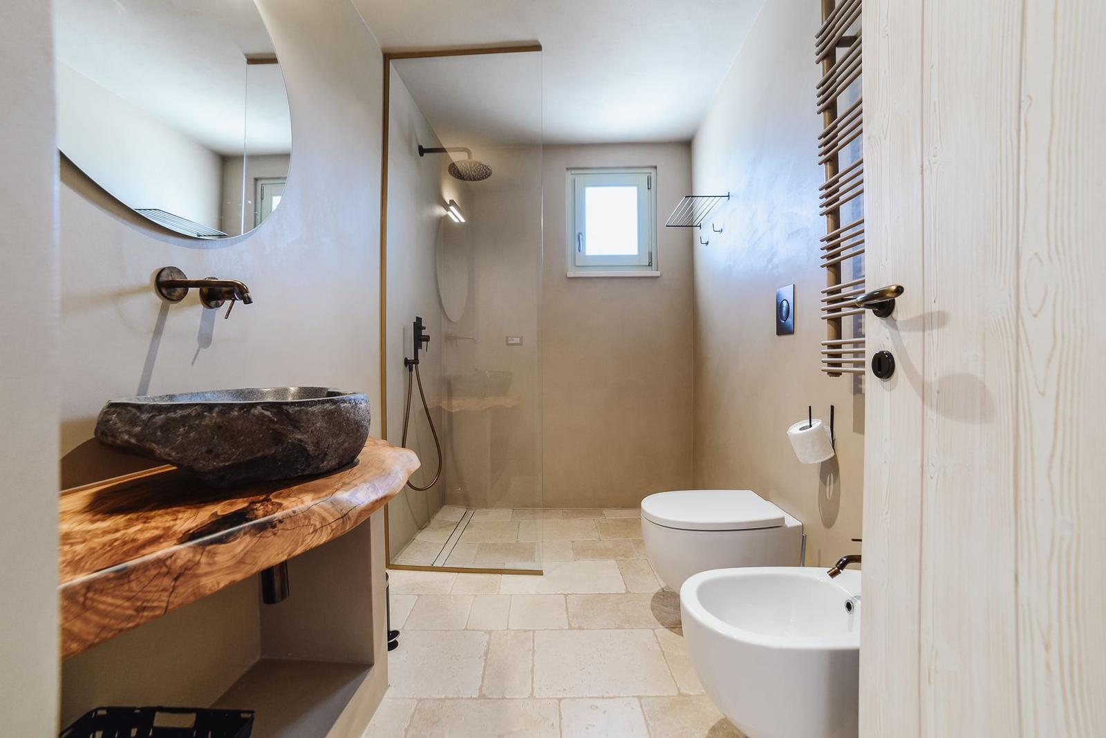 Bathroom with stone sink, shower, and toilet
