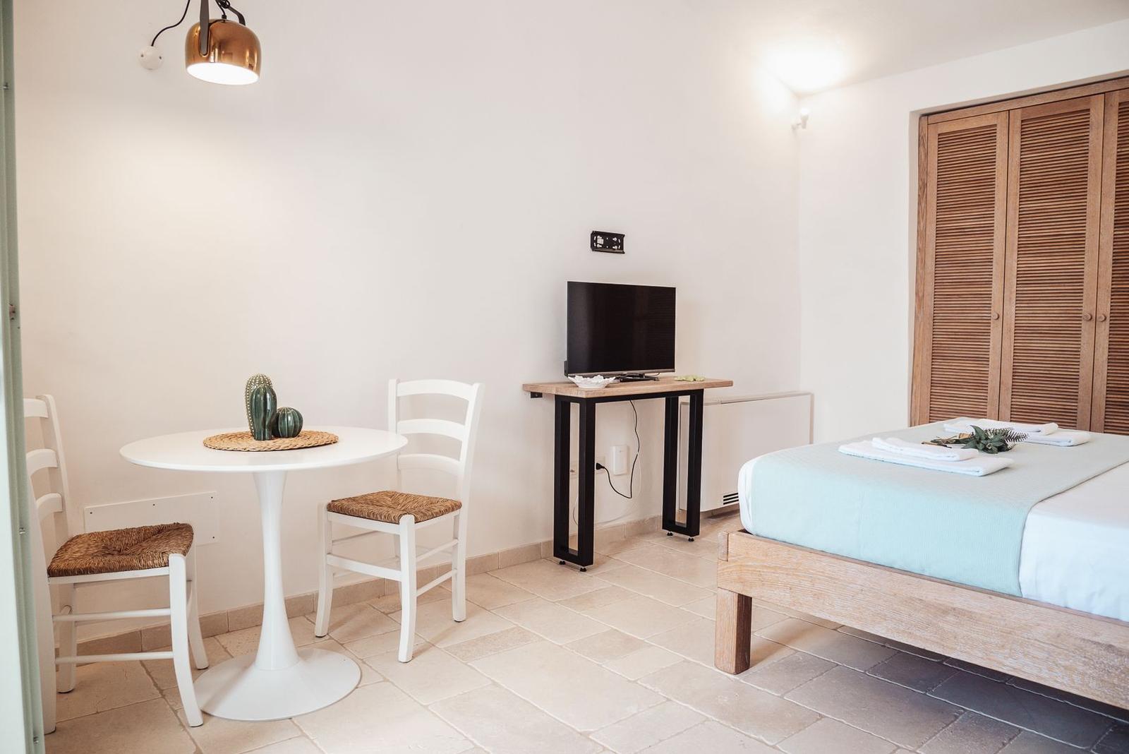 Room with bed, desk, TV, and round table with chairs.