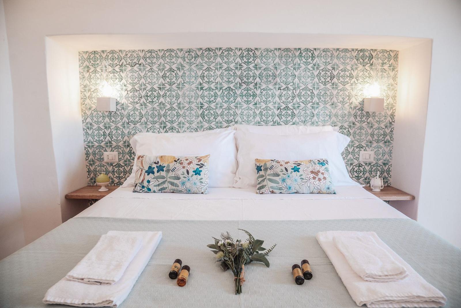 Double bed with mosaic tile headboard and two wooden shelves.