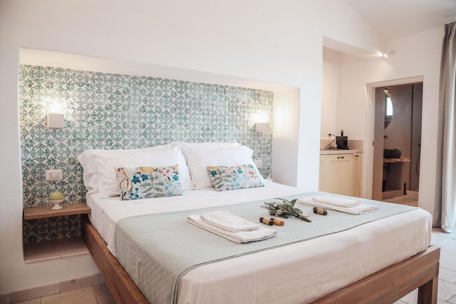 Bedroom with bed, decorative wall, and adjacent bathtub.