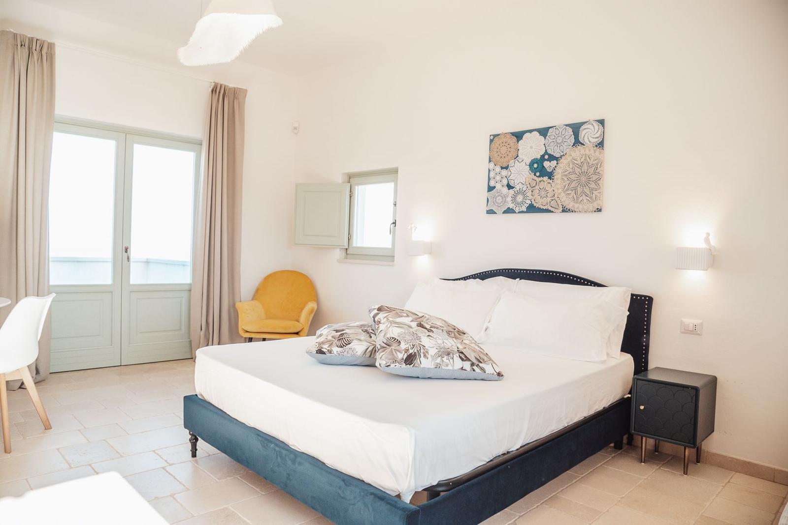 Schlafzimmer mit Bett, Nachttisch, Stuhl und Fenster.