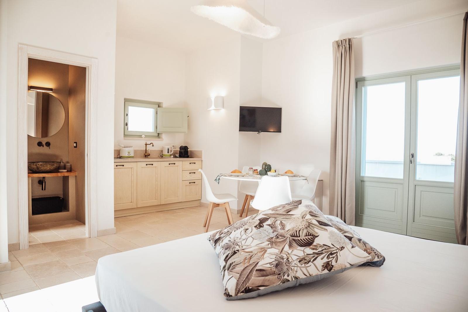 Schlafzimmer mit kleiner Küche, Essplatz und Bad im Hintergrund.